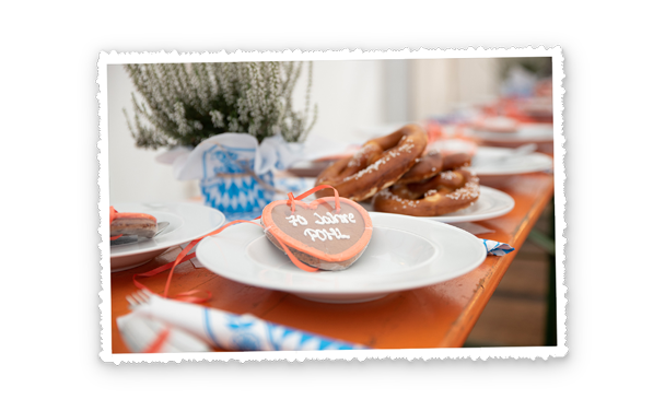 Gedeckter Tisch mit Tellern und Brezeln, im Vordergrund liegt ein Lebkuchenherz mit der Aufschrift 70 Jahre Pohl.