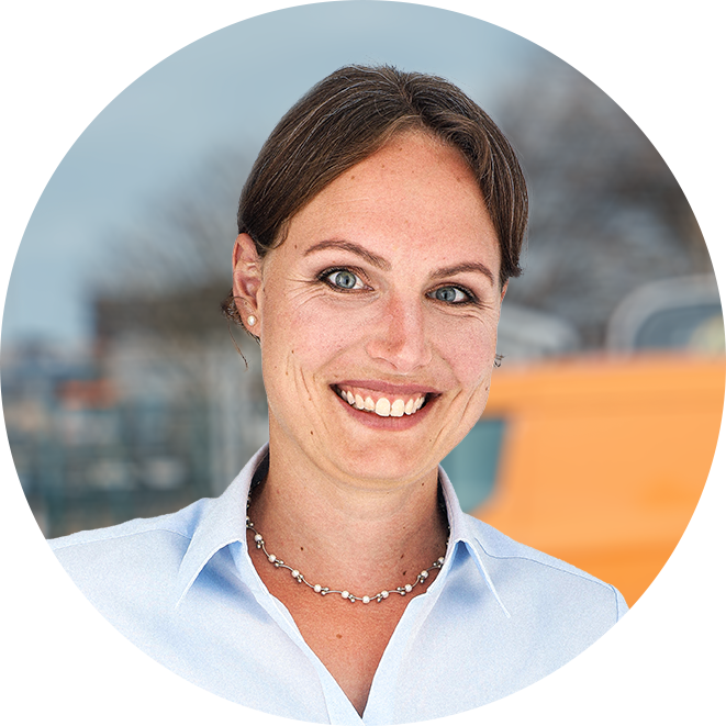 In der Mitte steht eine weibliche Person mit mittelbraunen, zum Nacken zurückgenommenen Haaren. Sie trägt eine hellblaue Bluse und eine Halskette; im Hintergrund rechts steht ein orangefarbenes POHL-Fahrzeug.