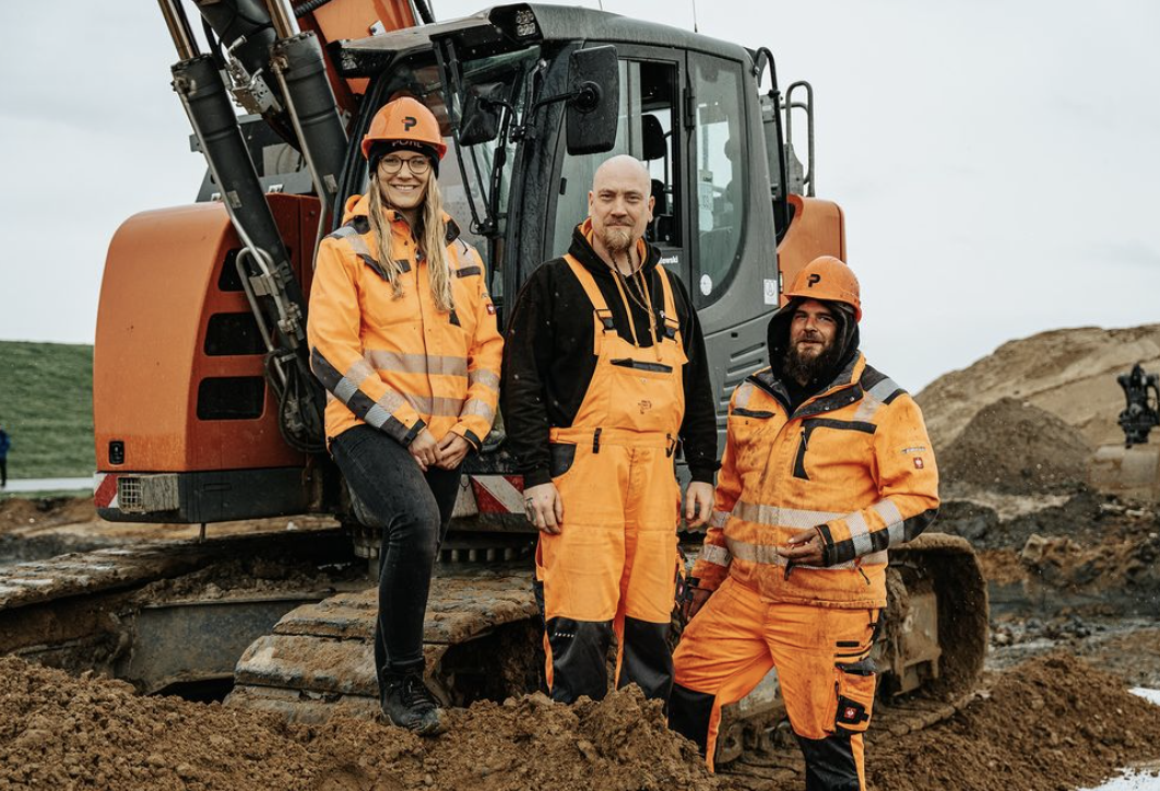 In der Mitte stehen drei POHL-Mitarbeiter in orange Schutzkleidung und Helmen vor einem orangefarbenen POHL-Bagger. Vorne im Bild liegt aufgewühlter Boden; im Hintergrund sind Erdhaufen und Baumaschinen zu erkennen.