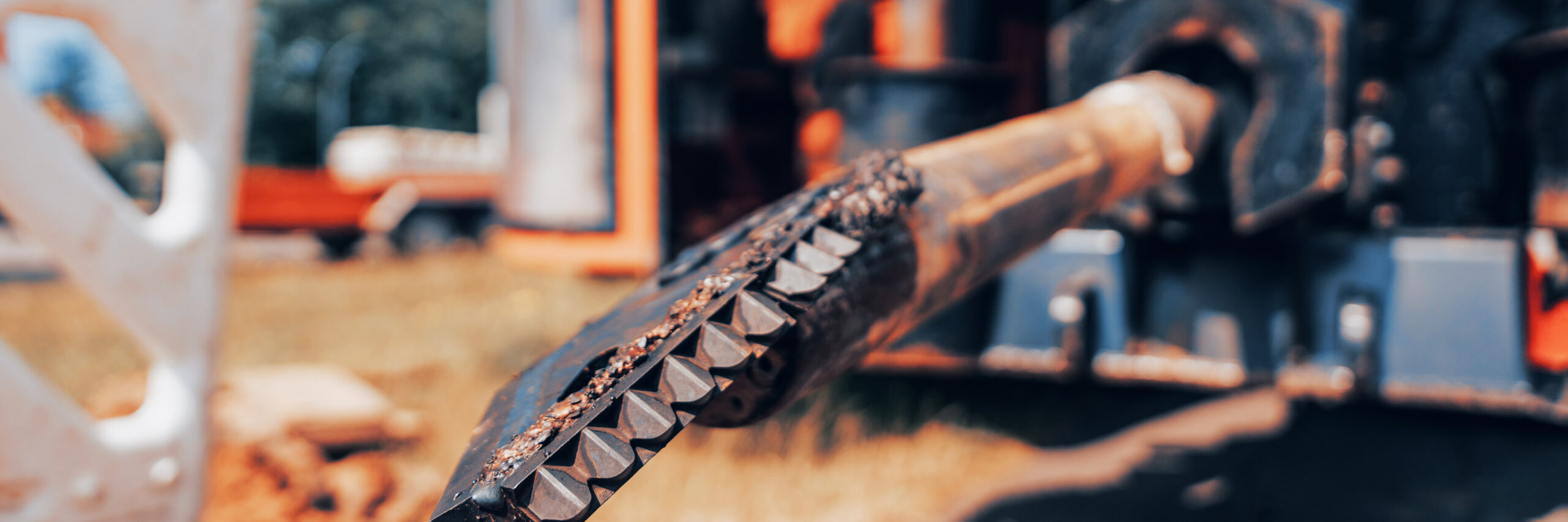 Nahaufnahme eines schweren Bohrkopfes, der mit Erde bedeckt ist.