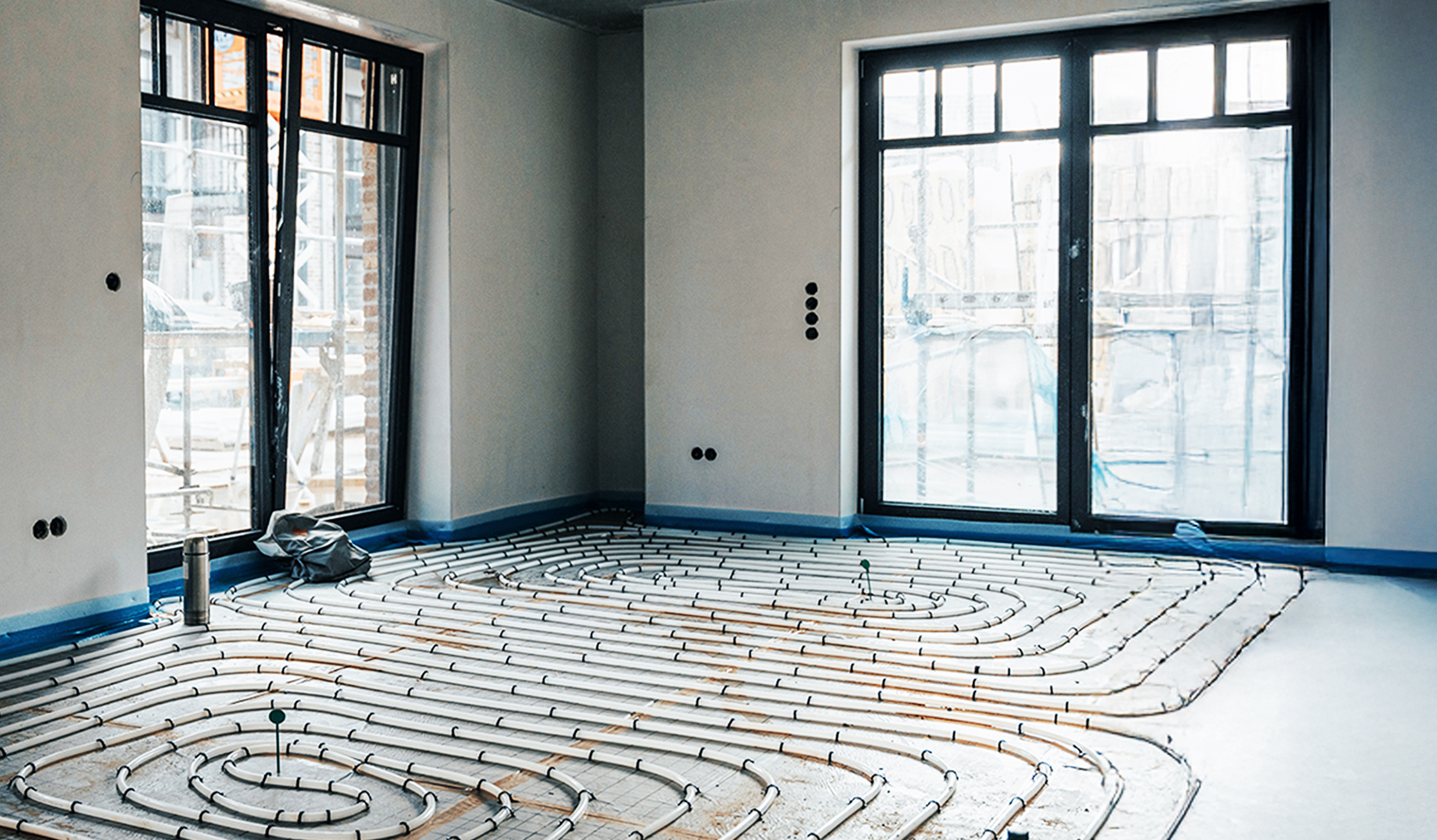 Ein heller Neubau-Raum mit verlegten Heizungsrohren im Boden, die spiralförmig angeordnet sind.