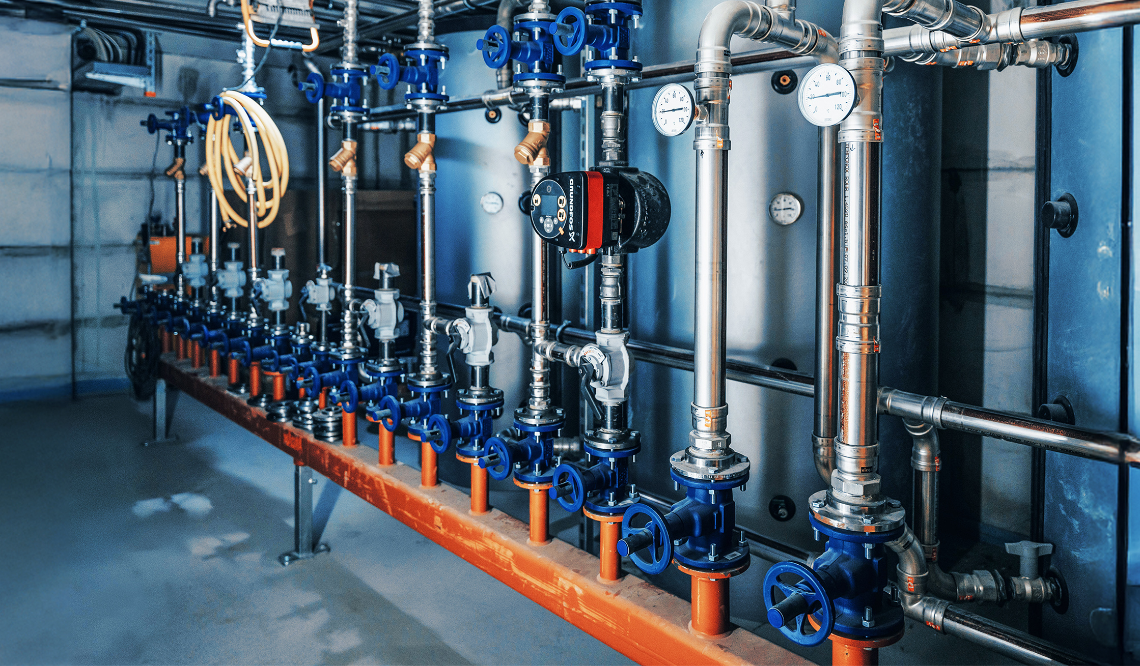Technikraum mit Rohren, Ventilen und Messgeräten für die Gebäudetechnik.