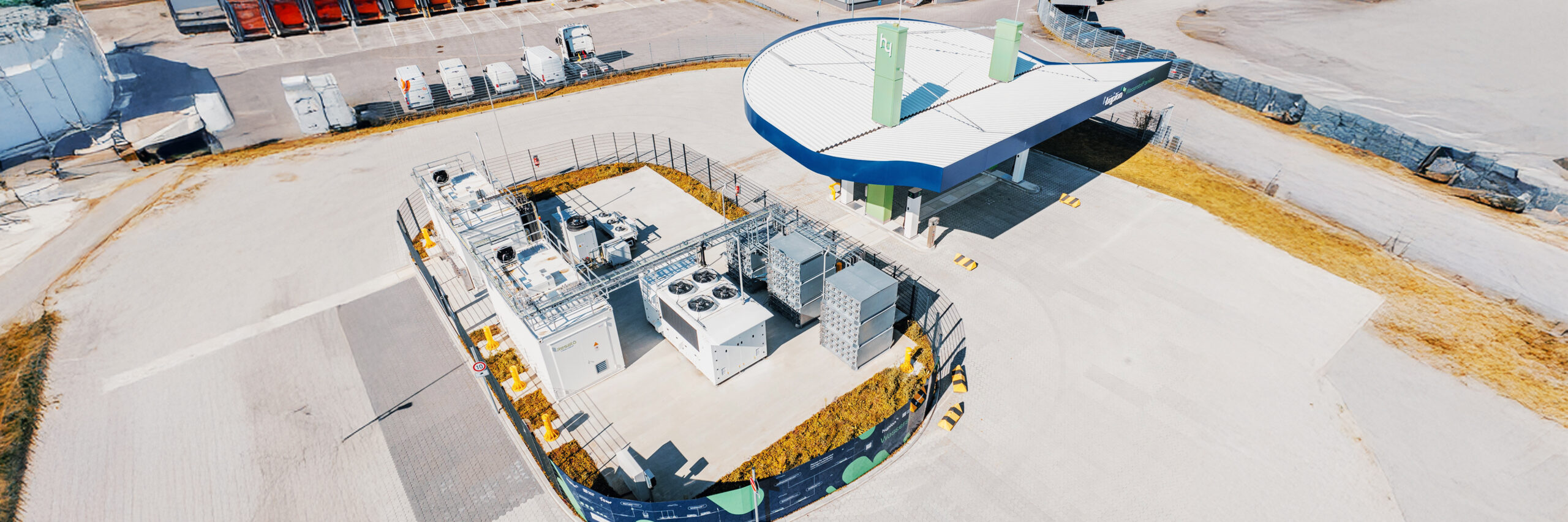 Referenz Hypion Wasserstofftankstelle Neumünster: Luftaufnahme einer modernen Wasserstoff-Tankstelle mit Überdachung, technischen Anlagen und angrenzenden Gebäuden.