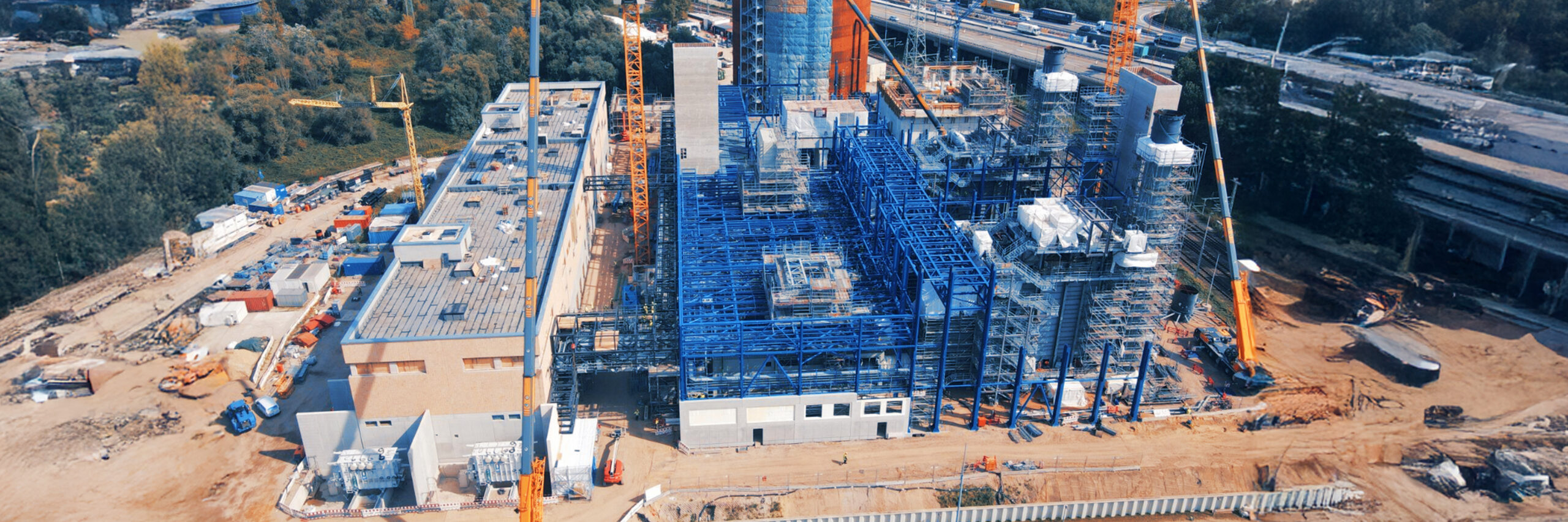 Industrieanlage mit Stahlkonstruktionen, Kränen und Gebäuden im Bau.