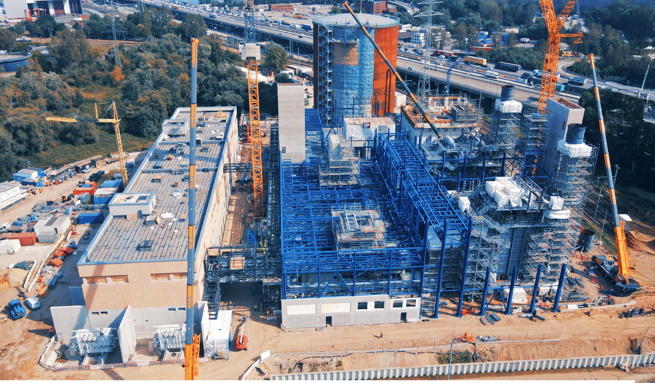 Industrieanlage mit Stahlkonstruktionen, Kränen und Gebäuden im Bau.