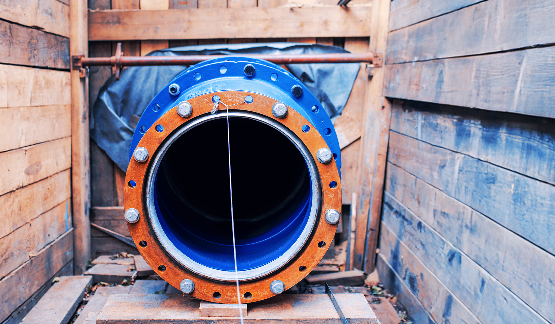 Großes blaues Rohrstück in einer Holzverschalung für Tiefbauarbeiten.