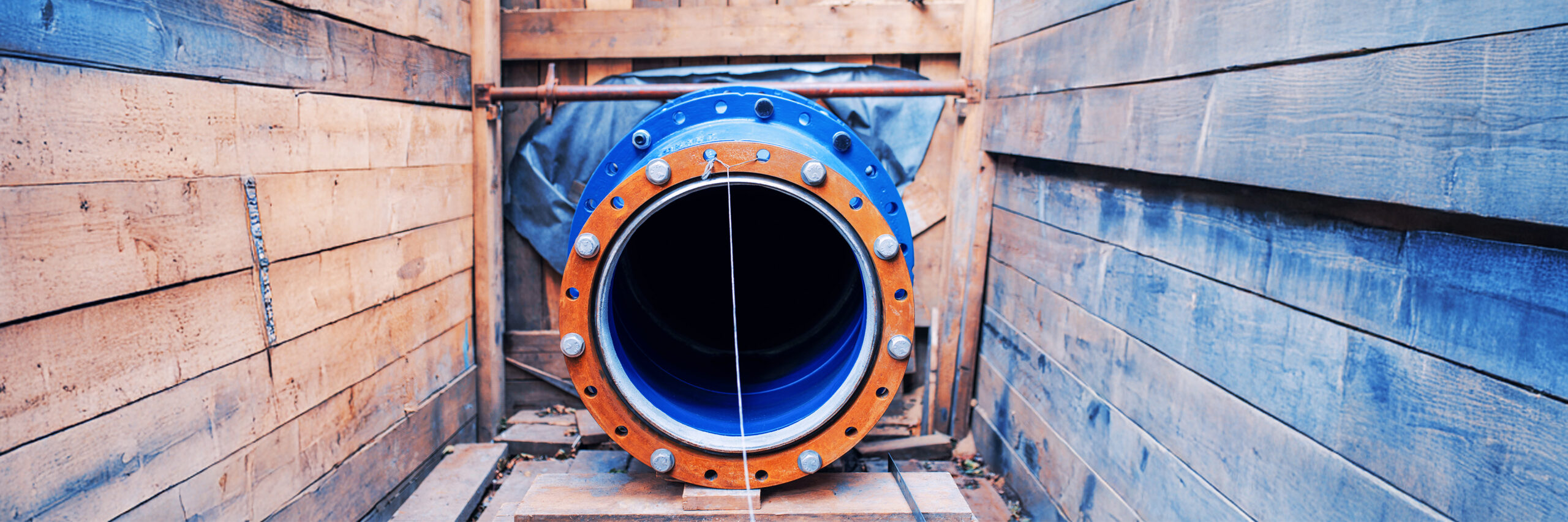 Großes blaues Rohrstück in einer Holzverschalung für Tiefbauarbeiten.