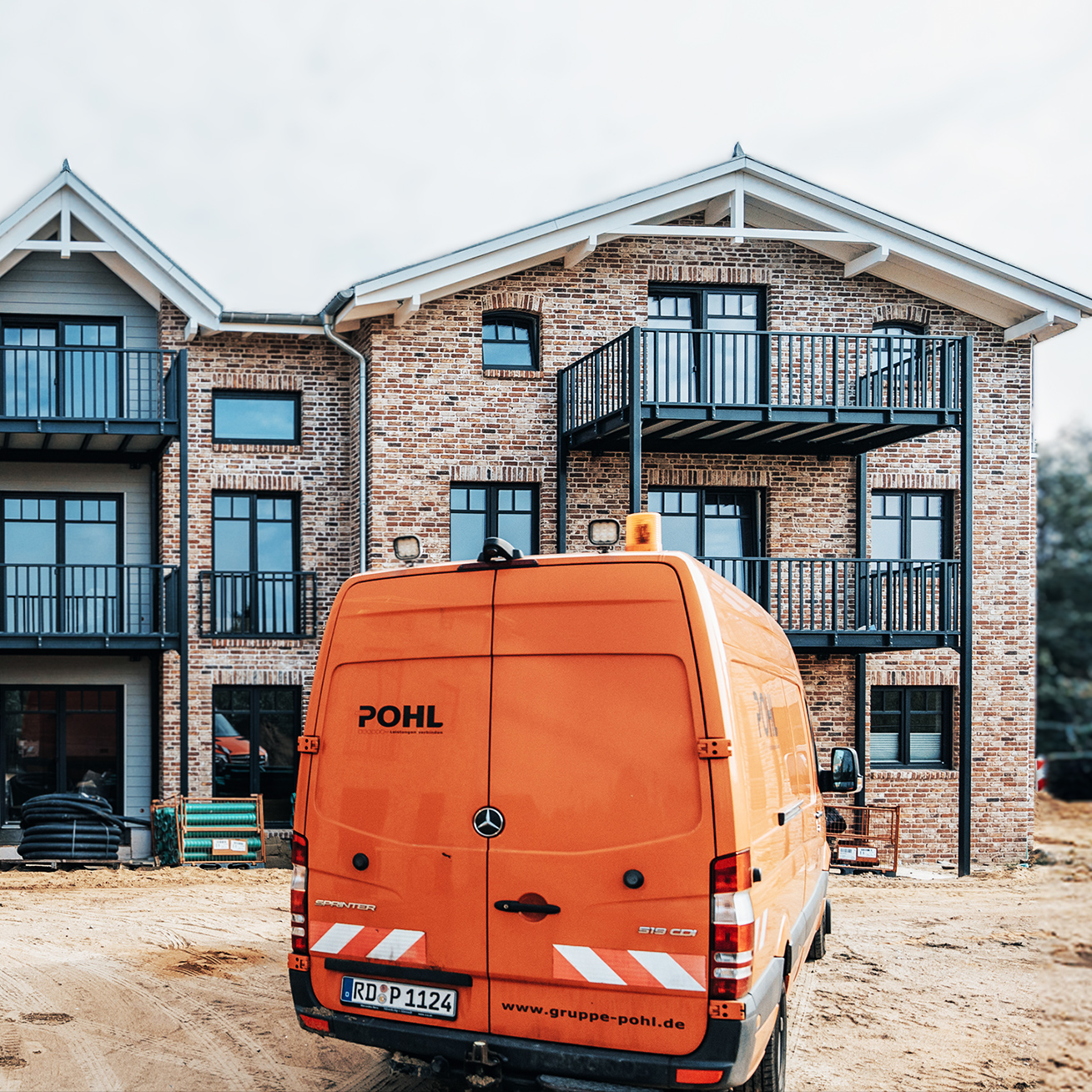 Referenz Mehrfamilienhäuser Büsum Johannsenallee: Backstein-Mehrfamilienhaus mit Firmenfahrzeug der Firma Pohl davor.