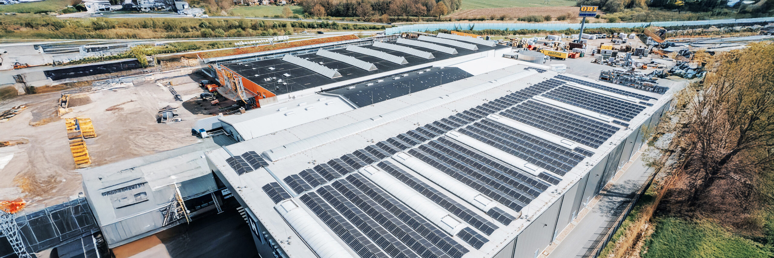 Luftaufnahme einer großen Dachfläche mit zahlreichen installierten Solarmodulen.