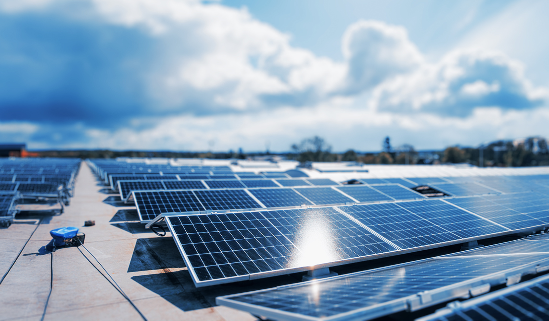 Reihe von Solarpanels auf einem großen Flachdach bei bewölktem Himmel.