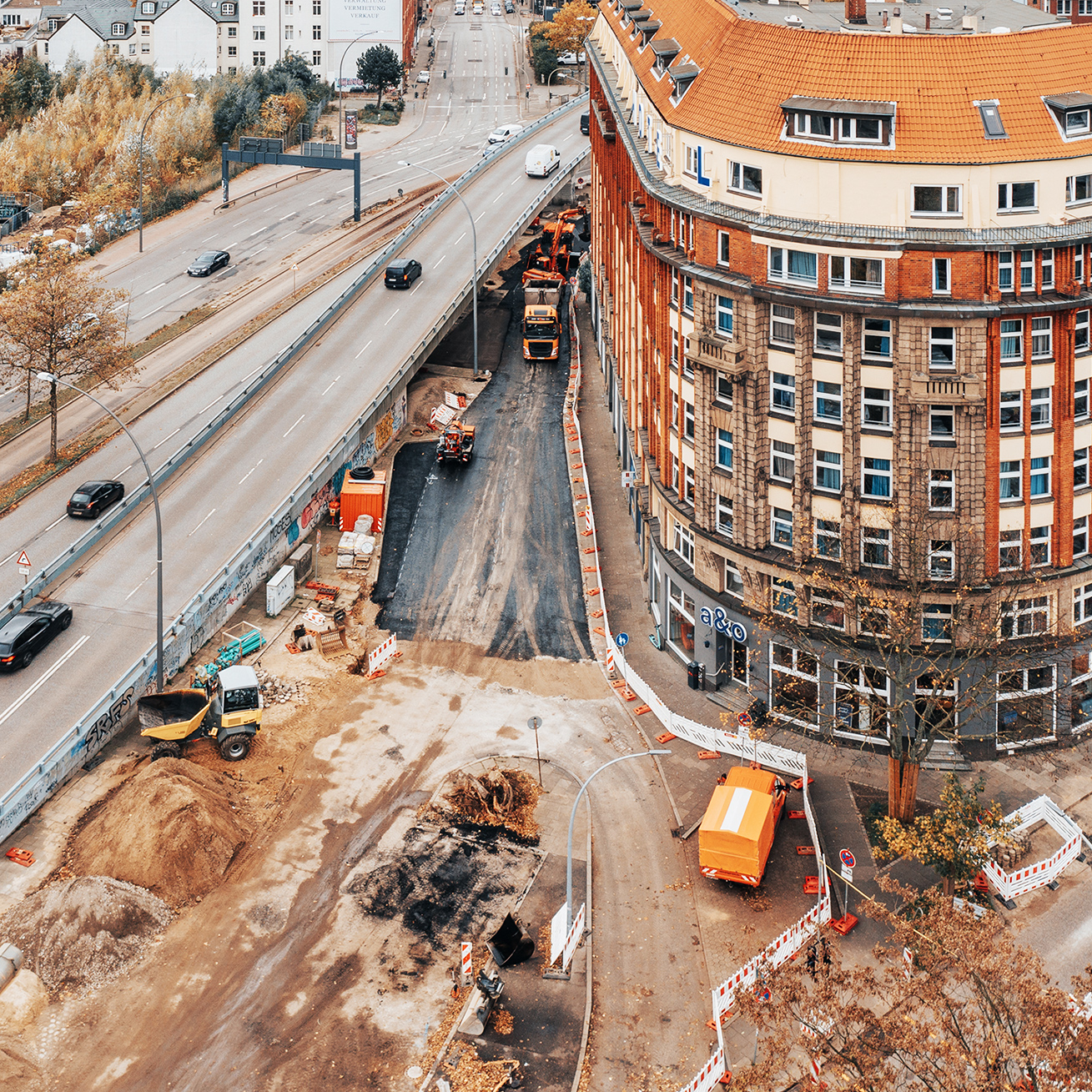 Referenz Umbau Hamburg Högerdamm: Baustelle vor runder Häuserfront, die Baustelle ist abgesperrt, Fahrzeuge von POHL auf der Baustelle.