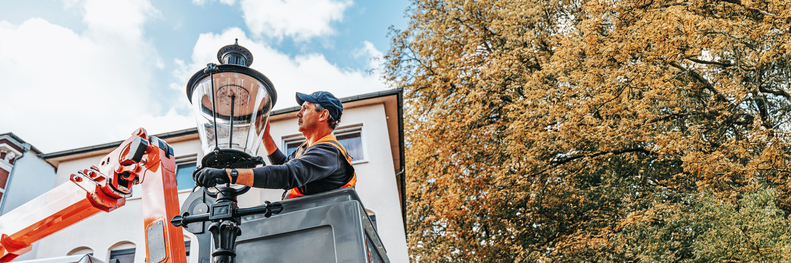 Mitarbeiter von POHL arbeitet aus einem Hubwagen an einer historischen Straßenlaterne.