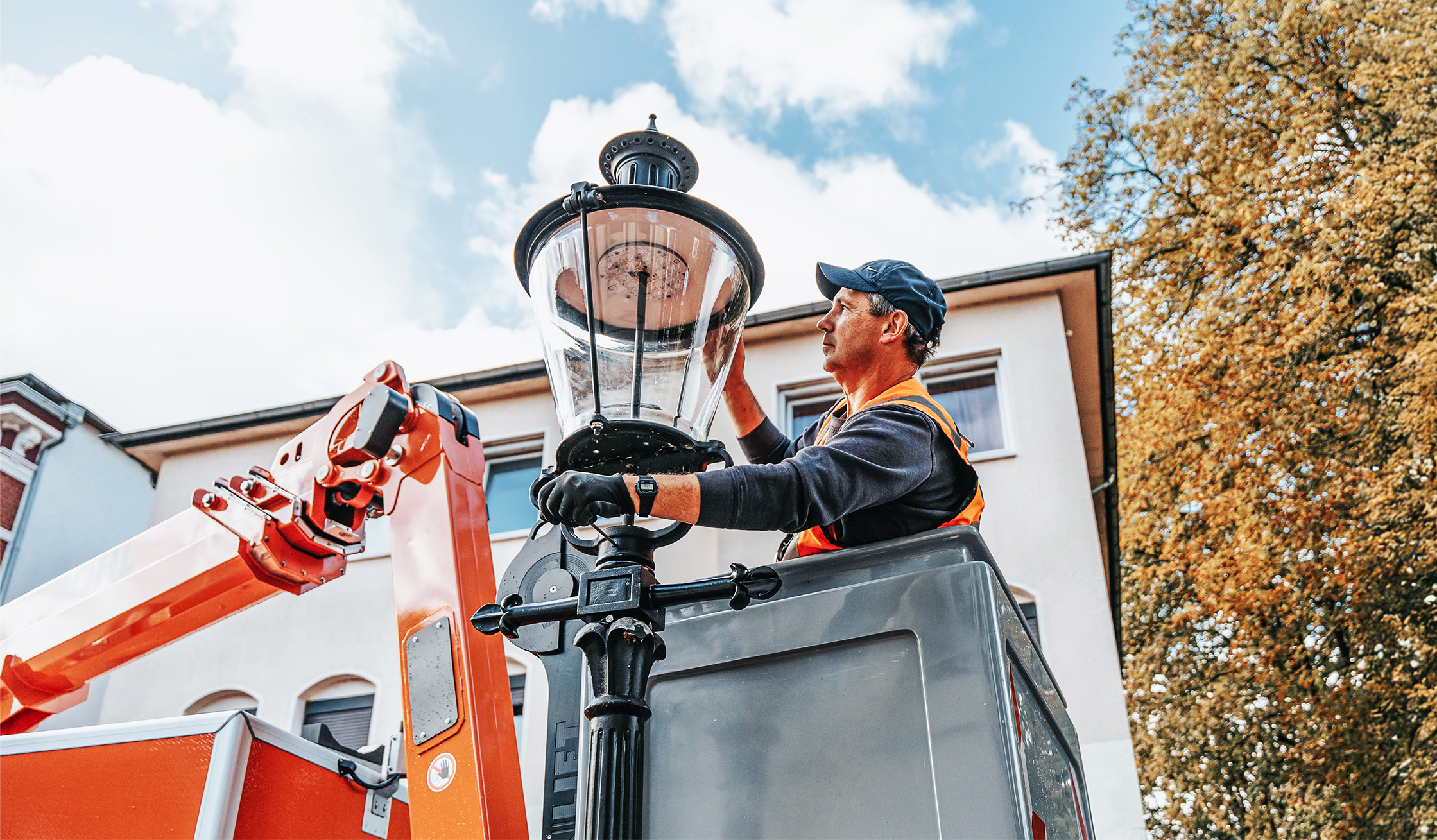Mitarbeiter von POHL arbeitet aus einem Hubwagen an einer historischen Straßenlaterne.