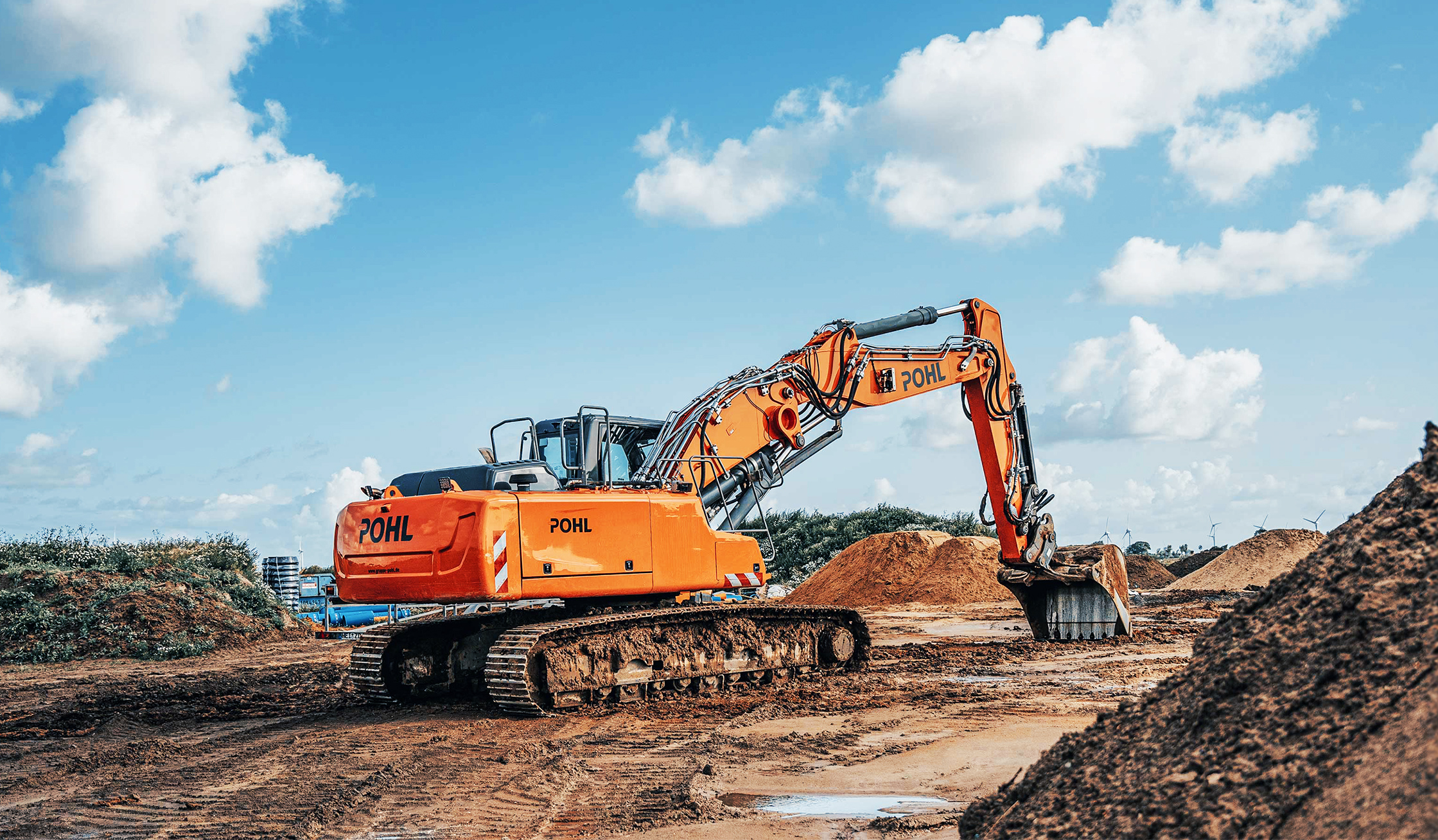 Großer Kettenbagger von POHL bewegt Erde auf einer Baustelle im Freien.