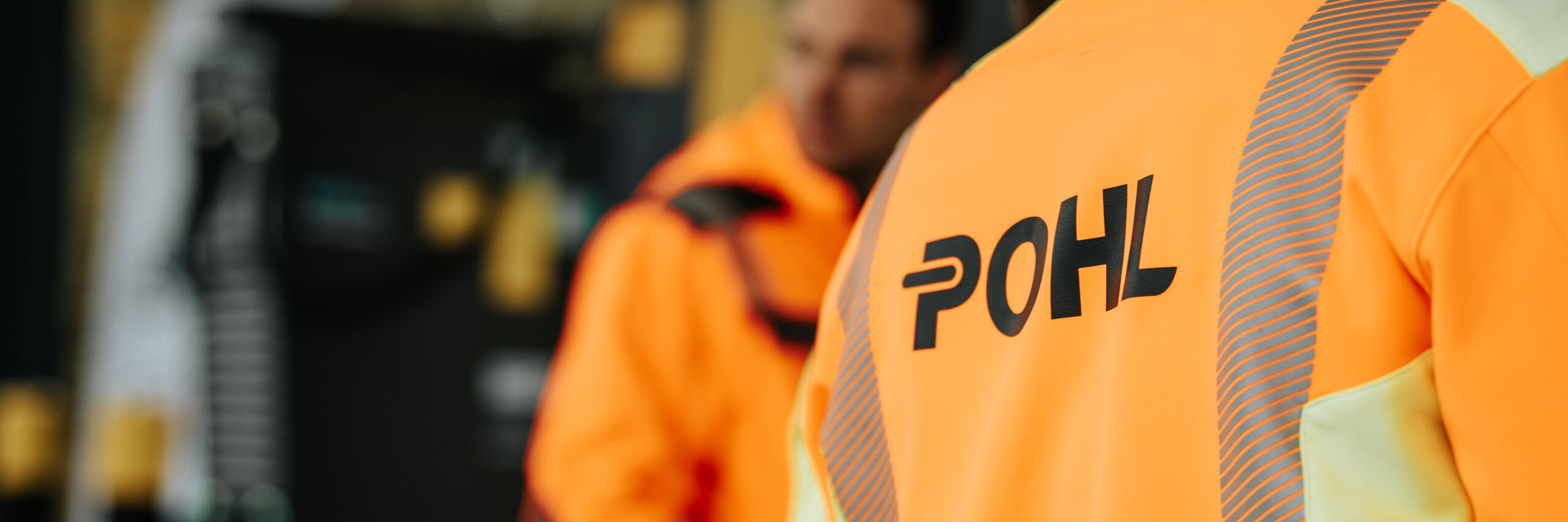 Rückseite einer orangen Jacke mit POHL Schriftzug
