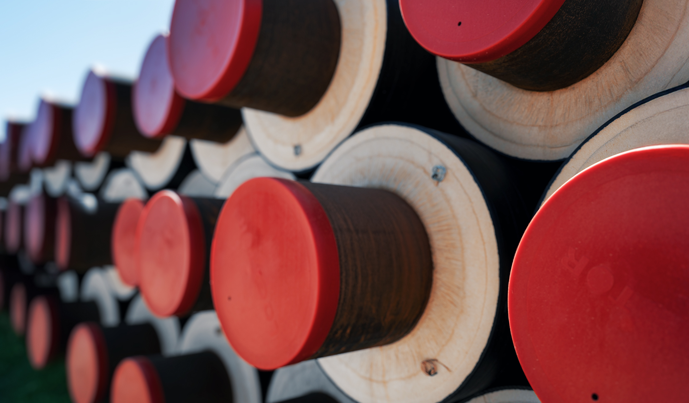 Wärmenetze: Nahaufnahme gestapelter isolierter Rohre mit roten Endkappen.