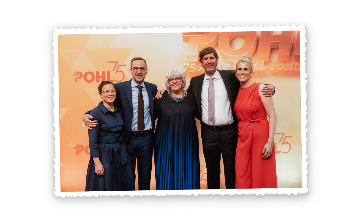 Fünf Erwachsene stehen nebeneinander vor einer orangefarbenen Rückwand mit Pohl 75 Schriftzug, alle schauen in die Kamera.